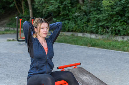 Young women doing sports on outdoor exercise machine in the stadium