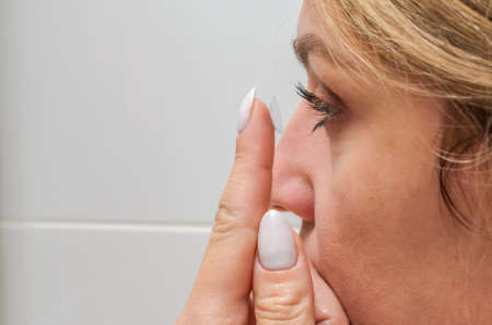 Young woman putting on contact lenses for vision correction