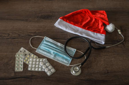 Red santa claus hat with stethoscope, medical mask and pillsの写真素材