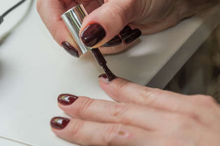 Woman doing a manicure to herself, painting nails with nail polish