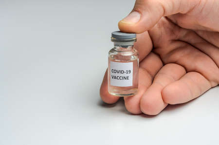 Ampoule with covid-19 coronavirus vaccine and syringe for injections on a white background
