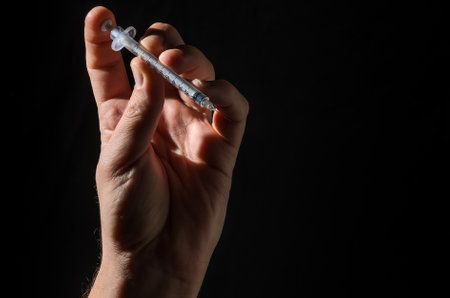 Hand with injection syringe on black backgroundの写真素材