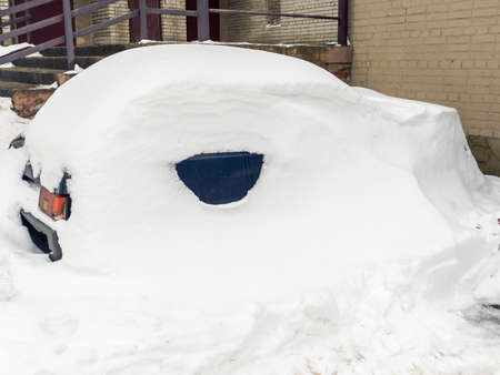 In winter, on a snow-covered street there are cars covered with snow