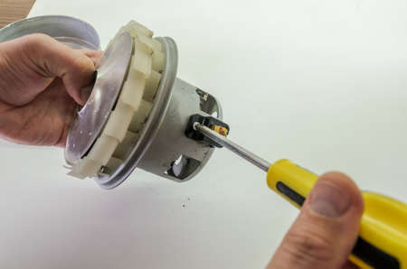 Service center foreman repairs the electric motor of the vacuum cleaner