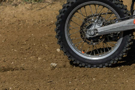 The wheel of a racing motocross motorcycle rides along the race track at high speed, stones and dust...