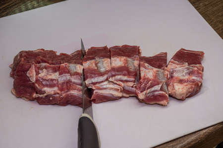 Butcher cuts lamb fillet with a knife on a cutting boardの写真素材