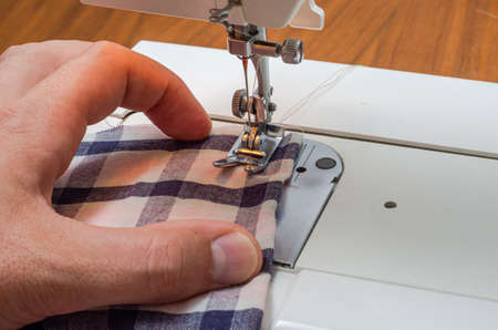 Tailor sews fabric for clothing on a sewing machine in a tailor shop