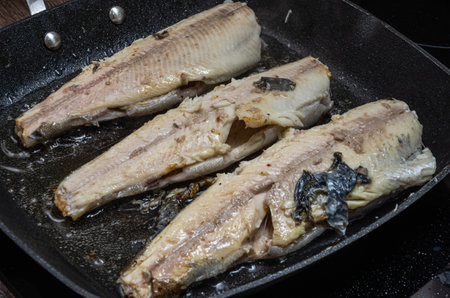 The cook fries rainbow trout fish in a pan