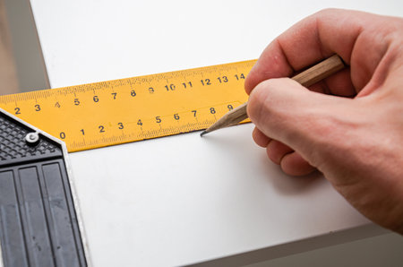 The master furniture maker draws a line, marking the size on the furniture plate with the help of a...