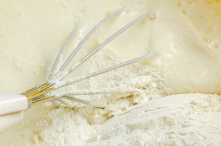 The cook beats the flour with a whisk into the dough for pancakesの写真素材