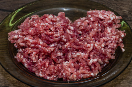 Minced meat in a plate on a wooden table, top viewの写真素材