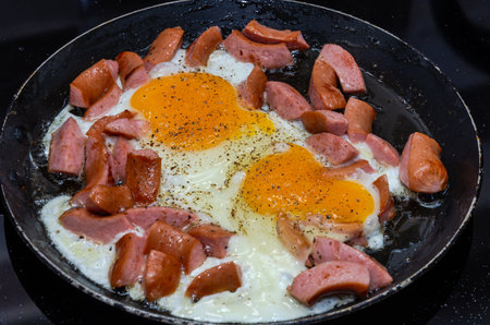 Fried eggs with sausages in a frying panの写真素材