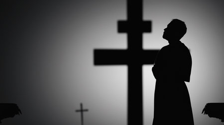 Silhouette of a woman praying in front of a cross.の素材