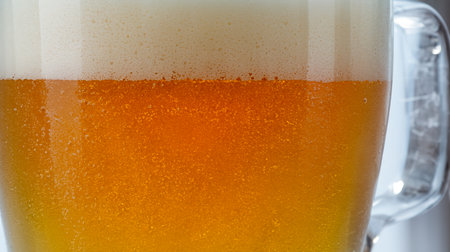 Close up of beer with foam in a glass on a white backgroundの素材