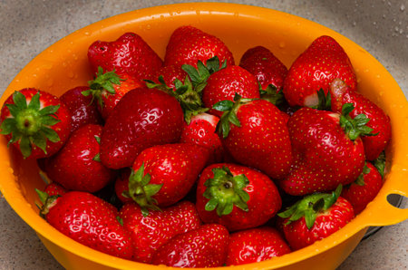 Strawberries in a yellow bowl on a kitchen countertop.の写真素材