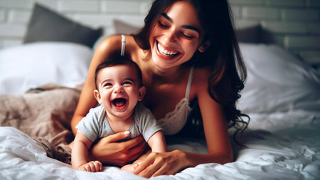 Happy mother with her little son playing on the bed at home.の素材