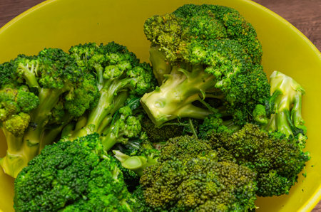 Broccoli in a yellow bowl on a wooden background. Selective focus.の写真素材