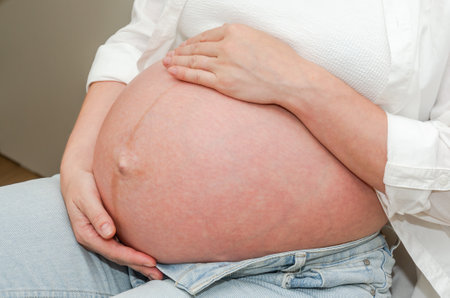 Pregnant woman touching her belly with hands, close up viewの写真素材
