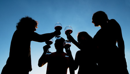 Six adults toasting with a glass of wine at sunset on the terraceの写真素材