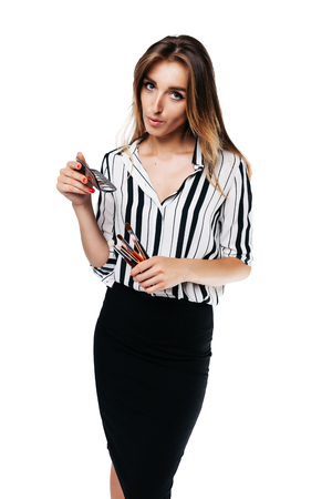 makeup artist girl in shirt and black skirt on a white background holding small eye shadow brushes and a palette in her handsの写真素材