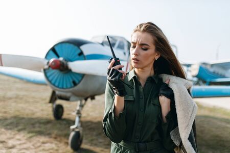 girl frowning eyebrows speaks into a walkie-talkie in a leather jacket on the background of the...