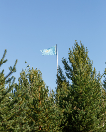 Kazakhstan flag on the flagpole behind the trees. Karaganda, Kazakhstanの写真素材