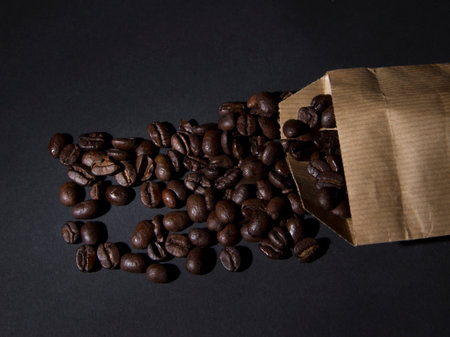 Scattered coffee grains in the paper package on the dark backgroundの写真素材
