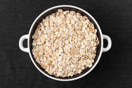 A lot of dry oatmeal lies in a plate on a dark backgroundの写真素材