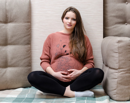 Beautiful pregnant woman relaxing at the homeの写真素材