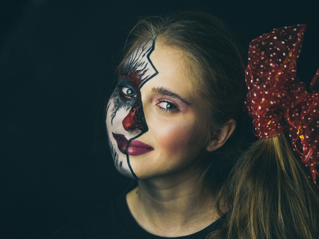 Portrait of a girl in makeup. Halloween, the face of a girl is a doll, the floor of a face is deadの写真素材