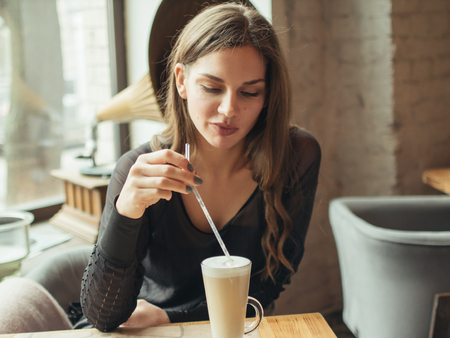 Young woman drinking coffee in a cafe. sweet foamの写真素材