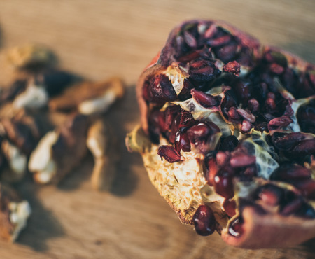 A beautiful but slightly dried up pomegranate on a wooden boardの写真素材