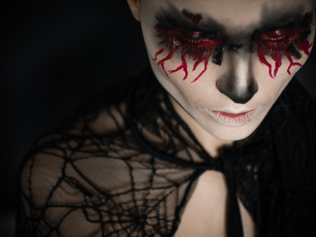 Portrait of a female vampire over black background.