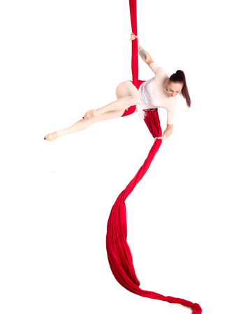 Woman hanging in aerial silks, isolated on white. Beautiful geometric poses.の写真素材