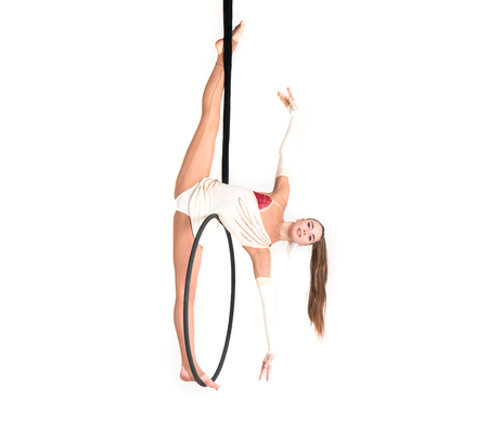 Young girl posing in an airy ring on a white background. Aerial hoop flyの写真素材