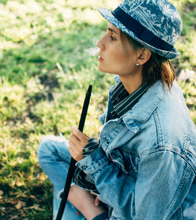 young woman at a picnic in the park smoking a hookah.
