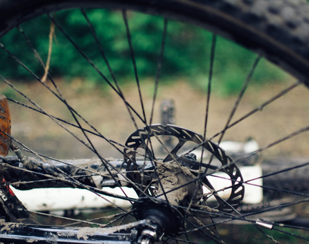 A dirty bike lies on the ground. The details are close-up, the wheels are dirty from a trip in bad weatherの写真素材