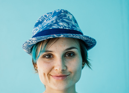 Close up portrait of attractive middle age woman smiling. Blue hat and blue background.の写真素材