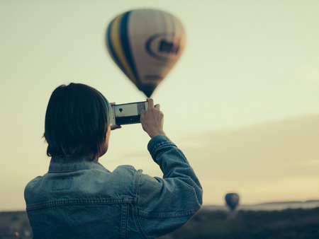 A young woman photographs a balloon flightの写真素材
