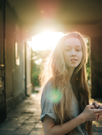 Red-haired young girl in the rays of sunset. City portrait.の写真素材