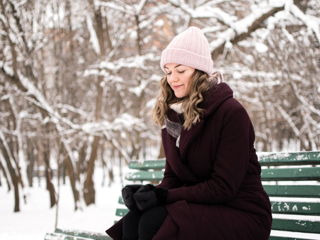 Happy pretty young woman in a snowy winter parkの写真素材