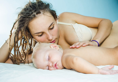 Little baby sleeps. Mum and daughter lie on the bed.の写真素材