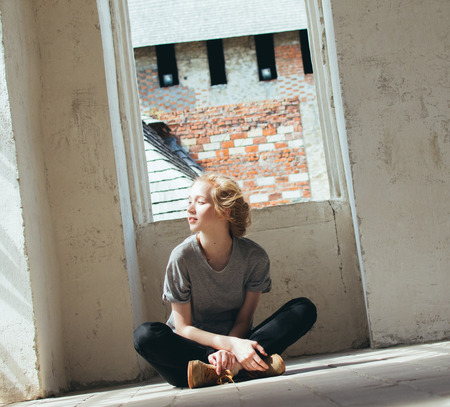 Beautiful young woman sits on the floor of the roomの写真素材
