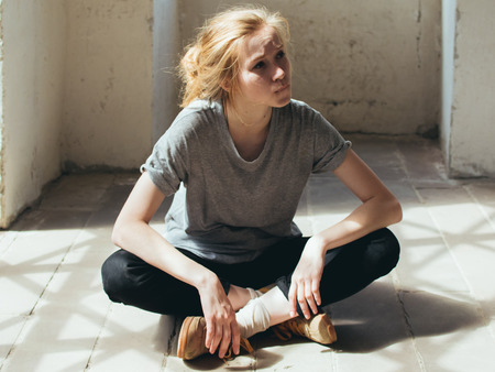 Beautiful young woman sits on the floor of the roomの写真素材