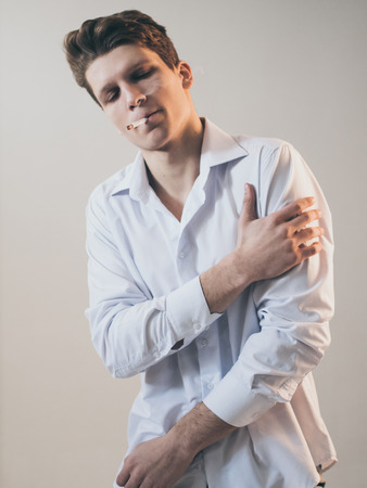 Young handsome guy man smoking a cigarette, studio shooting.の写真素材