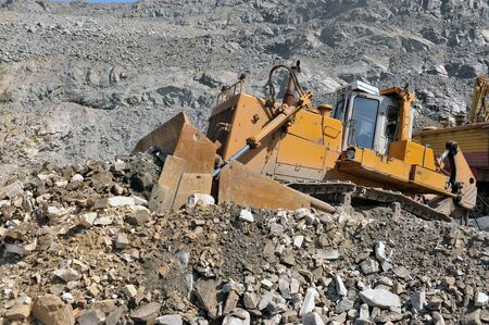 Wheel loader machine unloading rocks in the open-mine of iron ore