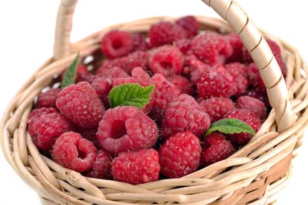 Fresh sweet raspberries in a wicker basket on white.