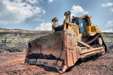 Wheel loader machine unloading rocks in the open-mine of iron ore