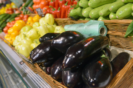 Eggplant and vegetables on display in supermarketの写真素材