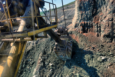 Close-up of an excavator bucket digging in earth and rock